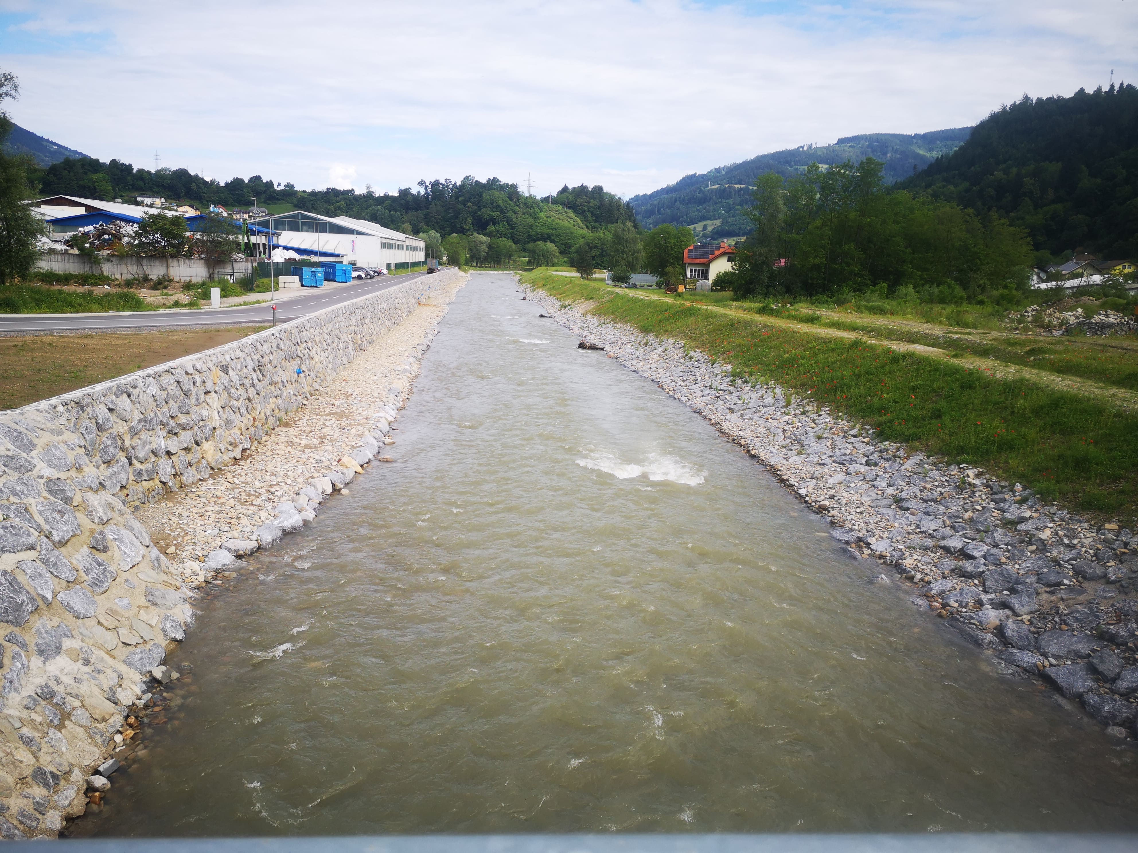 Gradnja protipoplavnih ureditev na Meži :zidovi, nasipi, trapezni profil struge, gruče skal samic, ribja skrivališče, medtem ko zasaditev avtohtonih vrst še ni bila izvedena. (Foto: P. Kralj, junij 2024). Gradnja protipoplavnih ureditev na Meži :zidovi, nasipi, trapezni profil struge, gruče skal samic, ribja skrivališče, medtem ko zasaditev avtohtonih vrst še ni bila izvedena. (Foto: P. Kralj, junij 2024).